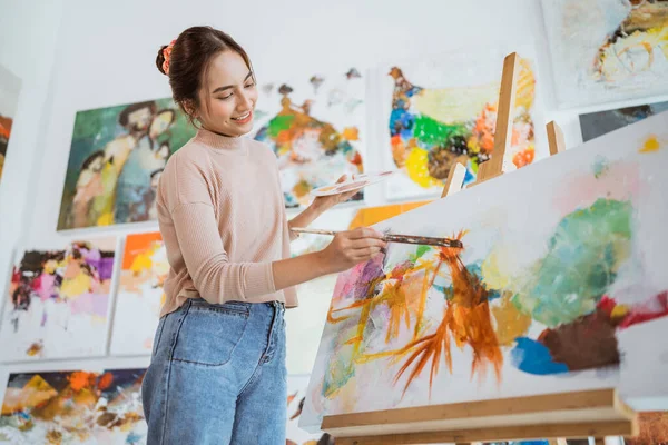 Asian female painter painting on canvas in her workshop — Stock Photo, Image