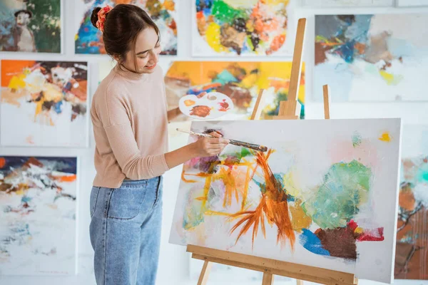 Asian female artist painting on canvas doing some art projects on her studio workshop — Stock Photo, Image