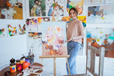 Asyalı kadın ressam atölyesinde tuvale resim yapıyor.