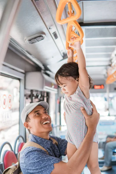 Батько і його дочка грають під час їзди на громадському транспорті, що звисає на барі — стокове фото