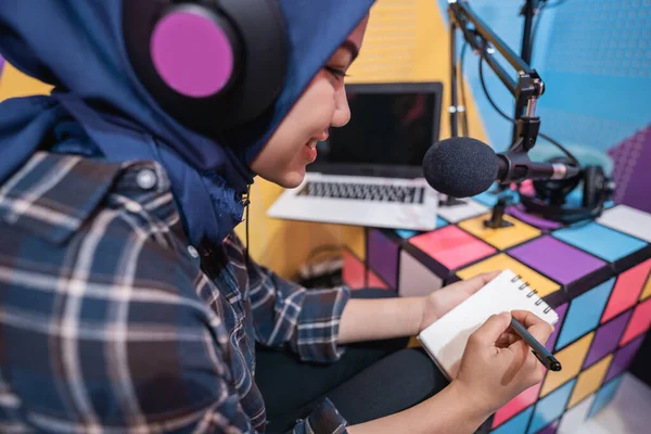 Muslim žena je nahrávání podcast ve studiu s notebookem s poznámkou s perem — Stock fotografie