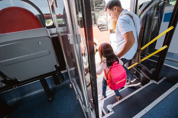 asian father taking his daughter to school by riding bus public transport