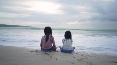 Kızlar kumsalda oturup eğleniyor ve eğleniyorlar.