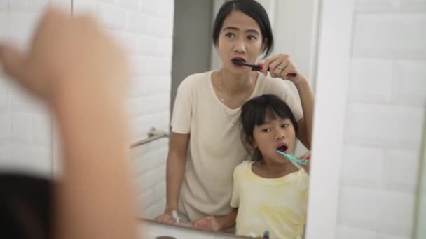 Мама и ребенок чистят зубы вместе — стоковое видео