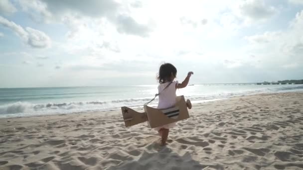 Garoto correr na praia brincar com avião de brinquedo feito de papelão — Vídeo de Stock