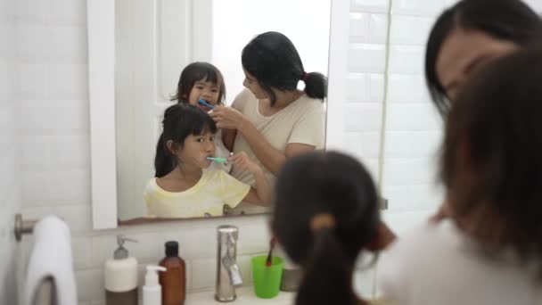 Счастливая азиатская мать и дочь чистить зубы вместе — стоковое видео