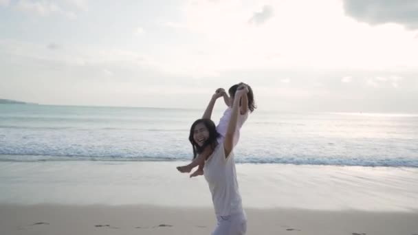 Anne sahilde kızını omuzlarında taşıyor. — Stok video