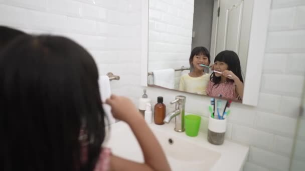 Две азиатские маленькие девочки чистят зубы вместе с братом и сестрой — стоковое видео