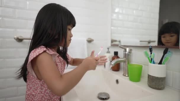 Asiático niña cepillos su dientes solo en el cuarto de baño — Vídeos de Stock