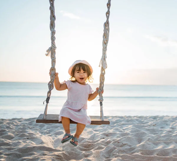 Glücklich kleines Mädchen schaukelt am Strand — Stockfoto