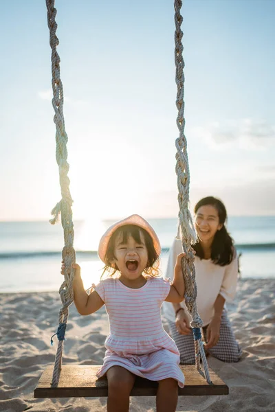 Menina feliz e mãe balançando na praia — Fotografia de Stock