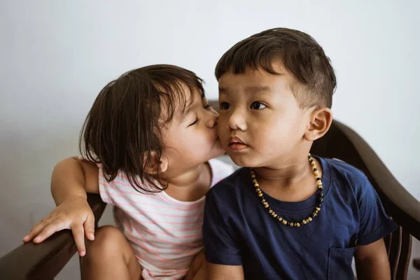 Liebender Bruder und kleine Schwester, die sich auf einem Stuhl umarmen — Stockfoto