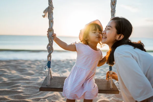 Fille embrasser sa mère tout en se balançant à la plage — Photo