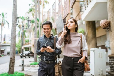 İş adamları kaldırımda yürüyor ve telefon kullanıyorlar.