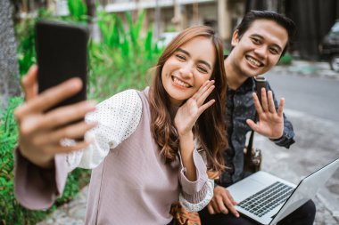 Mutlu kadın akıllı bir telefon kullanıyor. Ortağıyla selfie çekiyor ve görüntülü görüşme yapıyor.