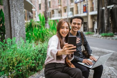 Mutlu kadın akıllı bir telefon kullanıyor. Ortağıyla selfie çekiyor ve görüntülü görüşme yapıyor.