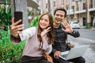 Mutlu kadın akıllı bir telefon kullanıyor. Ortağıyla selfie çekiyor ve görüntülü görüşme yapıyor.