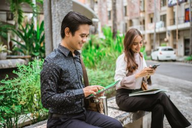 Ofis molasında parkta telefon kullanarak oturan iki meşgul işçi.