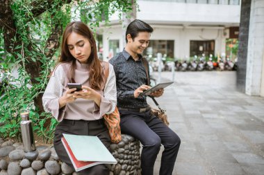 Ofis molasında parkta telefon kullanarak oturan iki meşgul işçi.