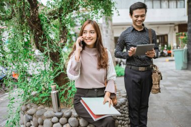Ofis molasında parkta telefon kullanarak oturan iki meşgul işçi.