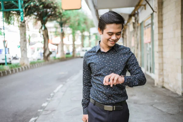 Hombre de negocios caminando por la acera sonriendo mirando su reloj de pulsera —  Fotos de Stock