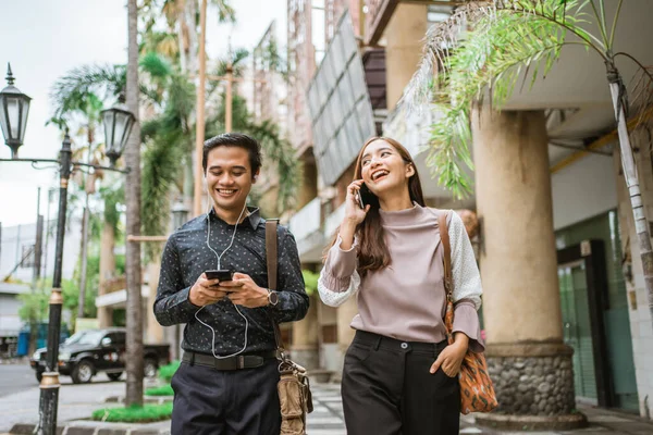 İş adamları kaldırımda yürüyor ve telefon kullanıyorlar.
