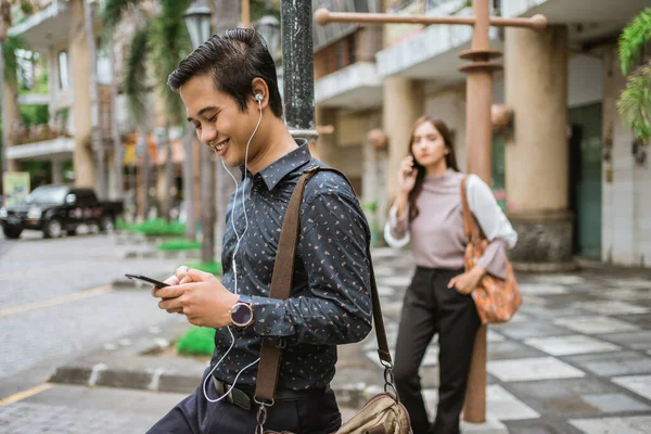 Erkek çalışan, ofis meydanında otobüs bekliyor.