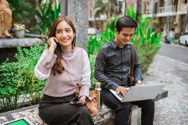 Slimme vrouw zit op een bank in het park naar muziek te luisteren — Stockfoto