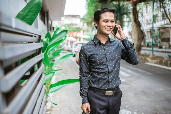 Geschäftsmann läuft lächelnd mit Handy über Bürgersteig ins Büro — Stockfoto