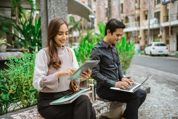 Nő használ tabletta fiatal férfi ül a parkban pad laptop — Stock Fotó