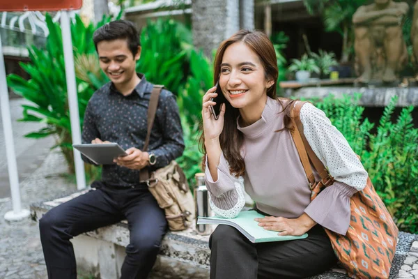 Twee drukke werknemer zitten in het park tijdens kantoorpauze met behulp van telefoon — Stockfoto