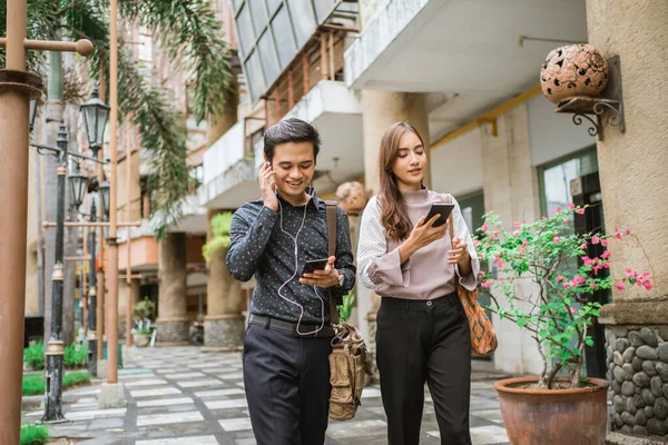 İş adamları kaldırımda yürüyor ve telefon kullanıyorlar.