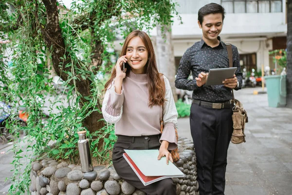 Ofis molasında parkta telefon kullanarak oturan iki meşgul işçi.