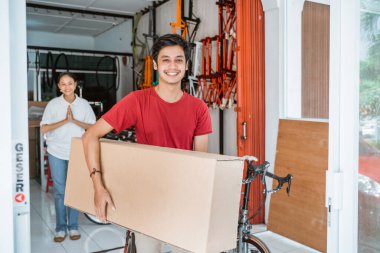 Adam yeni bir bisiklet alırken büyük bir kutu sökülmüş bisiklet taşıyor.