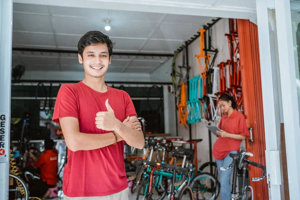 Hombre sonriendo con los pulgares en la tienda de bicicletas —  Fotos de Stock