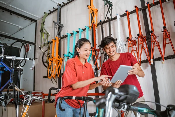 Vendedor y vendedora buscando nuevo modelo de bicicleta en la pantalla de la tableta —  Fotos de Stock