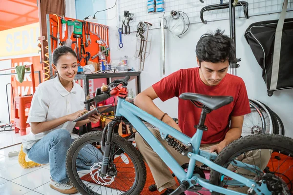 Joven mecánico montando una bicicleta nueva usando una llave inglesa en el taller —  Fotos de Stock