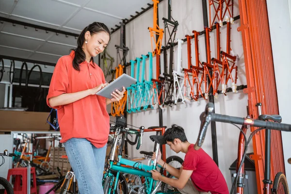 Donna che utilizza tablet contro un telaio di bicicletta in un negozio — Foto Stock