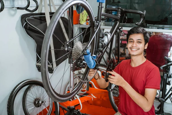 Mecánico en ropa roja trabajando cuidadosamente el montaje de un conjunto de manivela de bicicleta —  Fotos de Stock