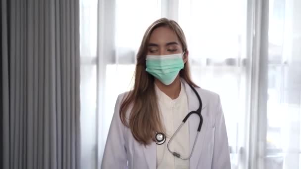 Женщина-врач в медицинской маске, стоящая, глядя в камеру — стоковое видео