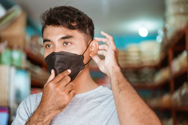 Pequeno empresário usando máscara facial na frente de sua loja — Fotografia de Stock
