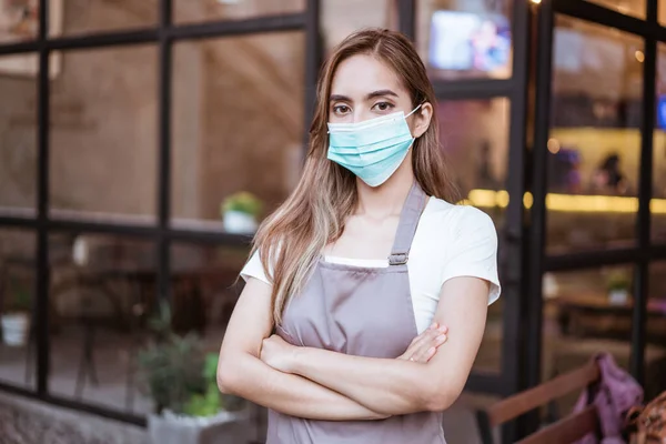 Serveerster met gezichtsmasker in de koffieshop — Stockfoto