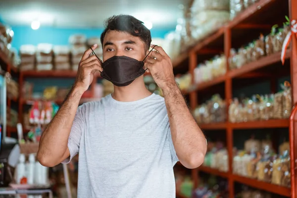 Dueño de una pequeña empresa con mascarilla en frente de su tienda — Foto de Stock