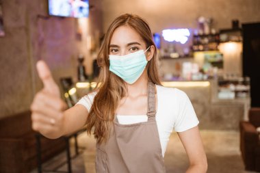 Kahve dükkanında yüz maskesi takan bir garson.