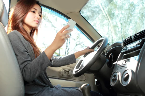 Jovem mulher mensagens de texto durante a condução — Fotografia de Stock