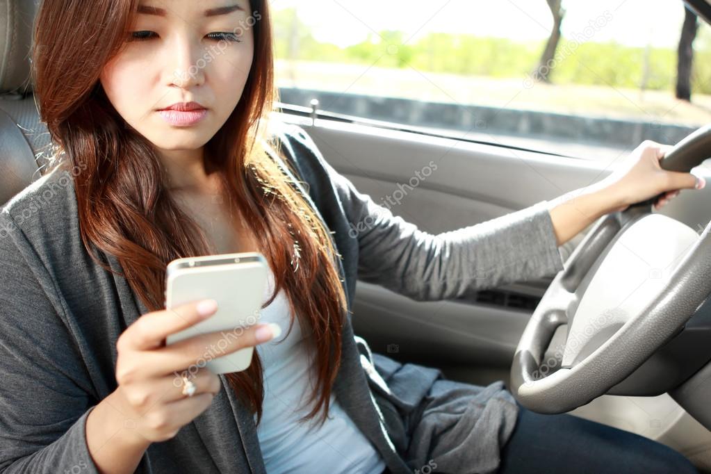 young woman texting while driving a car