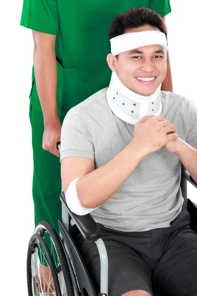 Injured young man in wheelchair help by nurse — Stock Photo, Image