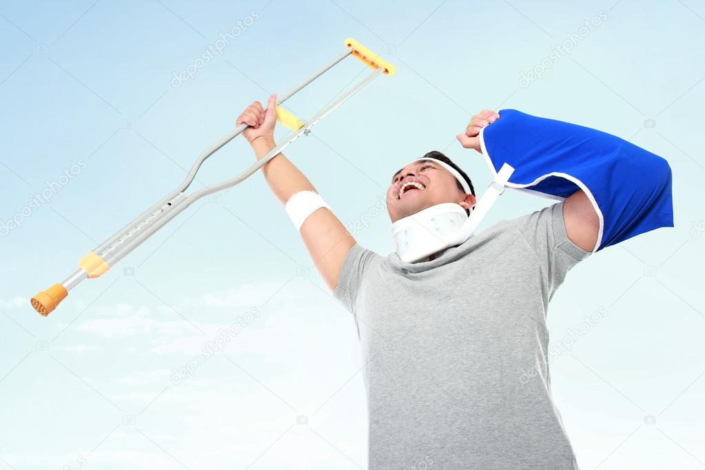 cheerful injured young man hold up the crutch