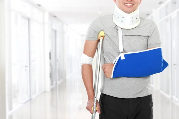 Homem jovem ferido usar muleta e braço sling — Fotografia de Stock