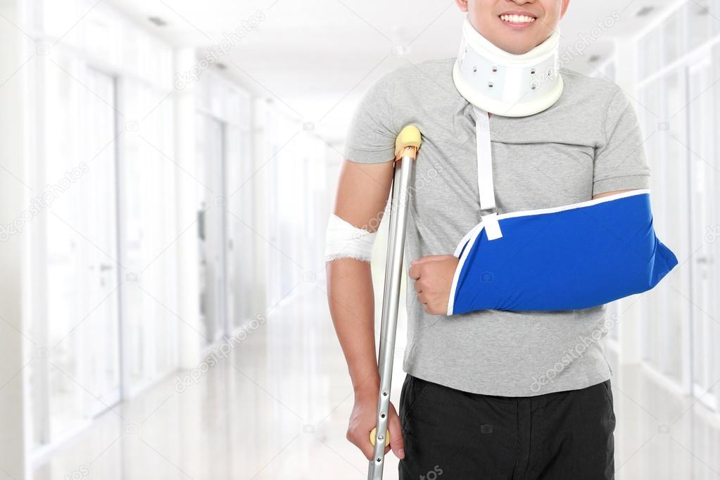 injured young man use crutch and arm sling